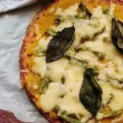 Small pizza with cheese and spinach leaves on a paper plate