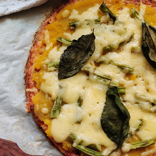 Small pizza with cheese and spinach leaves on a paper plate